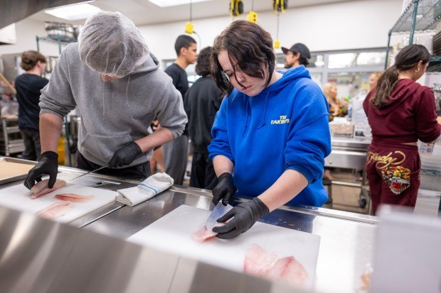 Students prepare fish for tacos during a cooking clinic at...