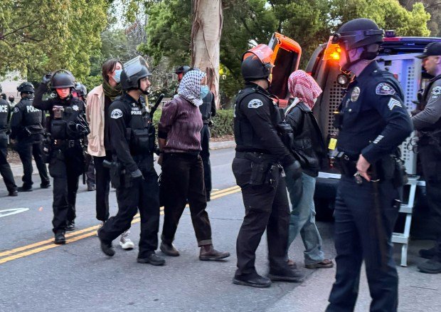 Police detain protesters near a transport vehicle on Friday, April...