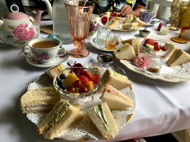 Tea sandwiches and scones are served with fresh fruit at...