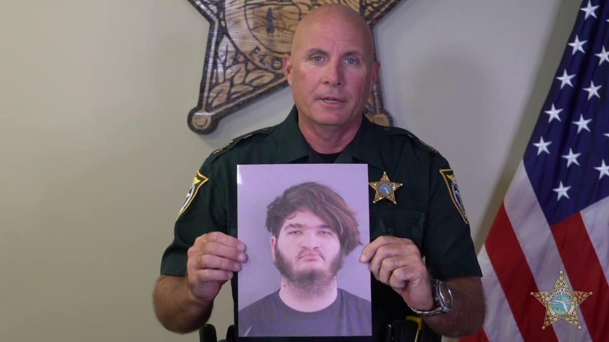 Undersheriff Pat Breeden holding photo of the murder suspect