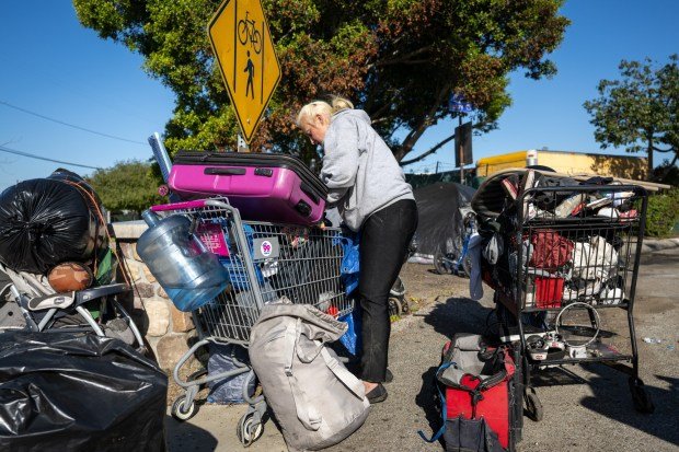 Kelly Wilson gathers her belongings at an encampment before moving into interim housing during a Pathway Home operation in Signal Hill on March 14. (Photo by Michael Owen Baker)