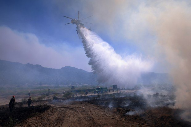 TOPSHOT – Air support drops water as the Post Fire...