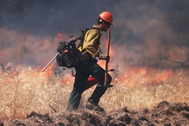 A US Forest Service firefighter sets a controlled burn as...