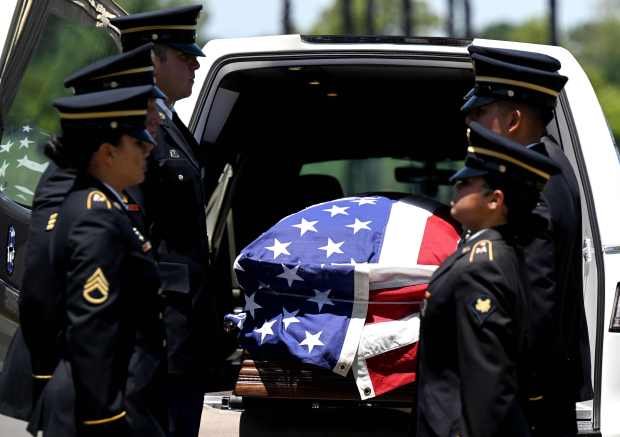 An honor guard detail prepare to remove the casket containing...