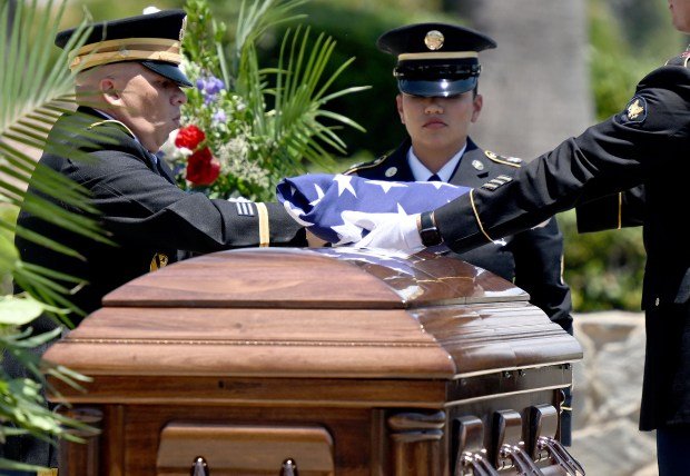 An honor guard detail fold the American flag above the...