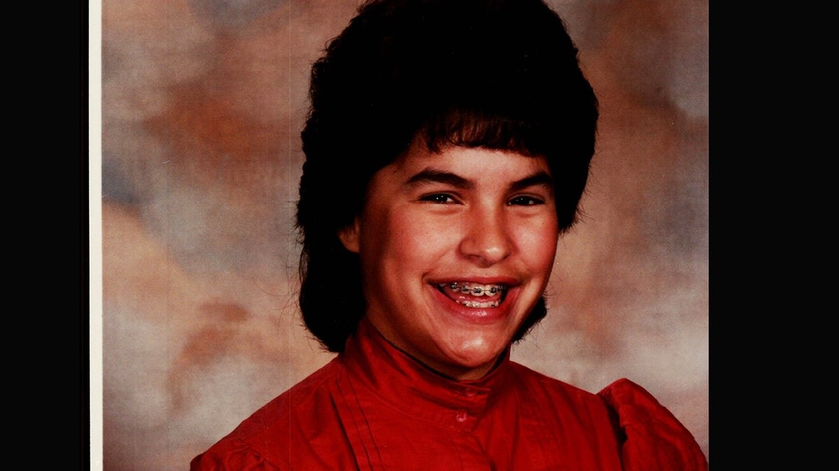 Jonelle Matthews smiling in a red turtleneck with braces