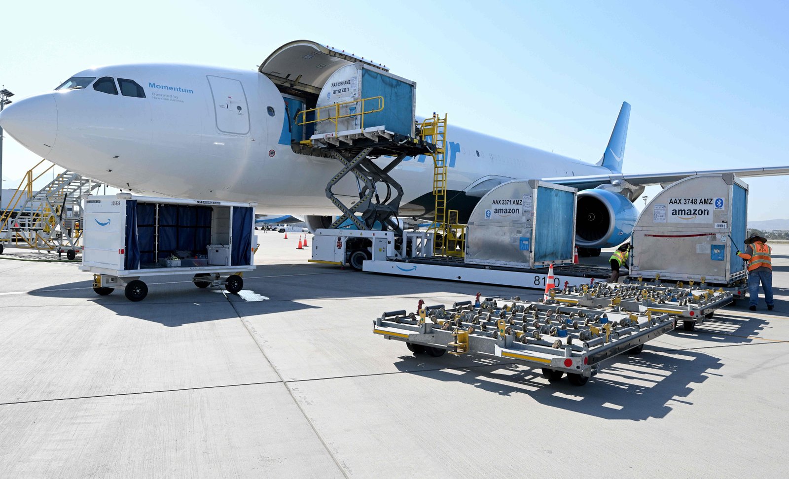 Amazon employees unload containers from a jet at the company’s...