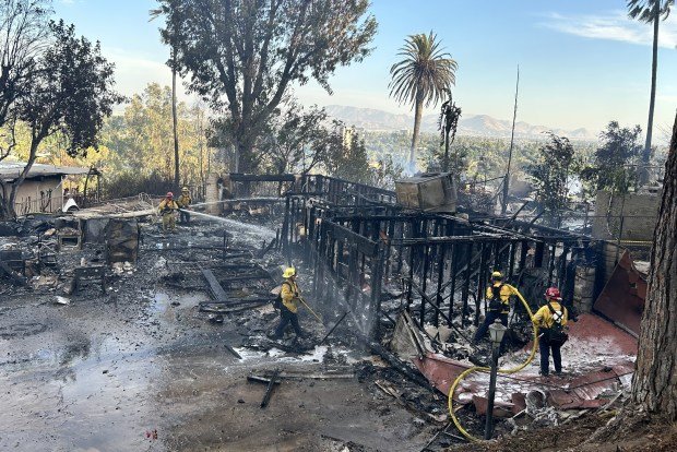 Firefighters put out the smoldering remains of homes on Vista...