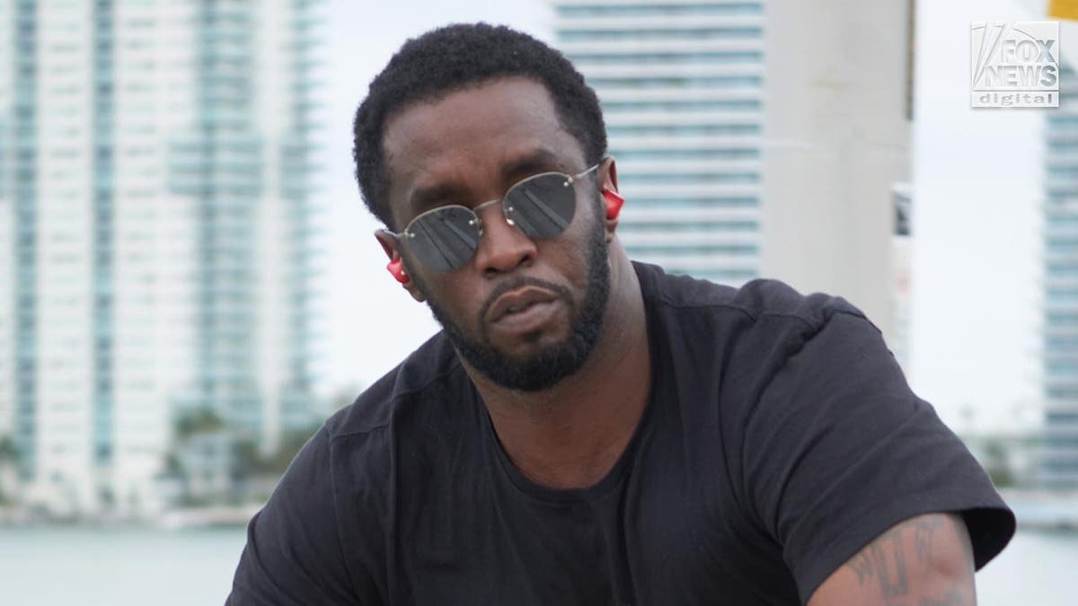 P Diddy looks at the camera wearing sunglasses as he rides his bicycle.